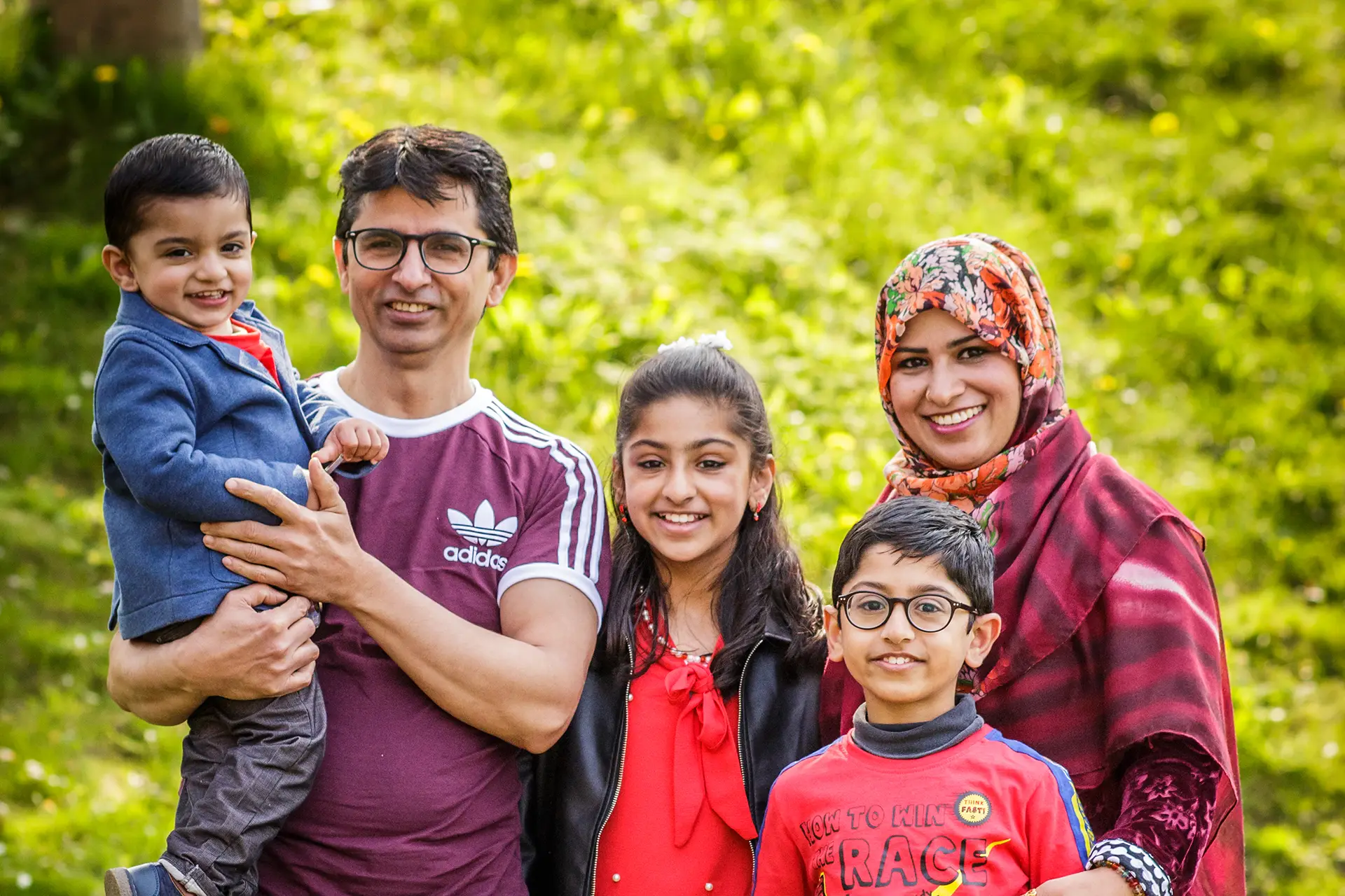 Family outdoors in green space, smiling for photo