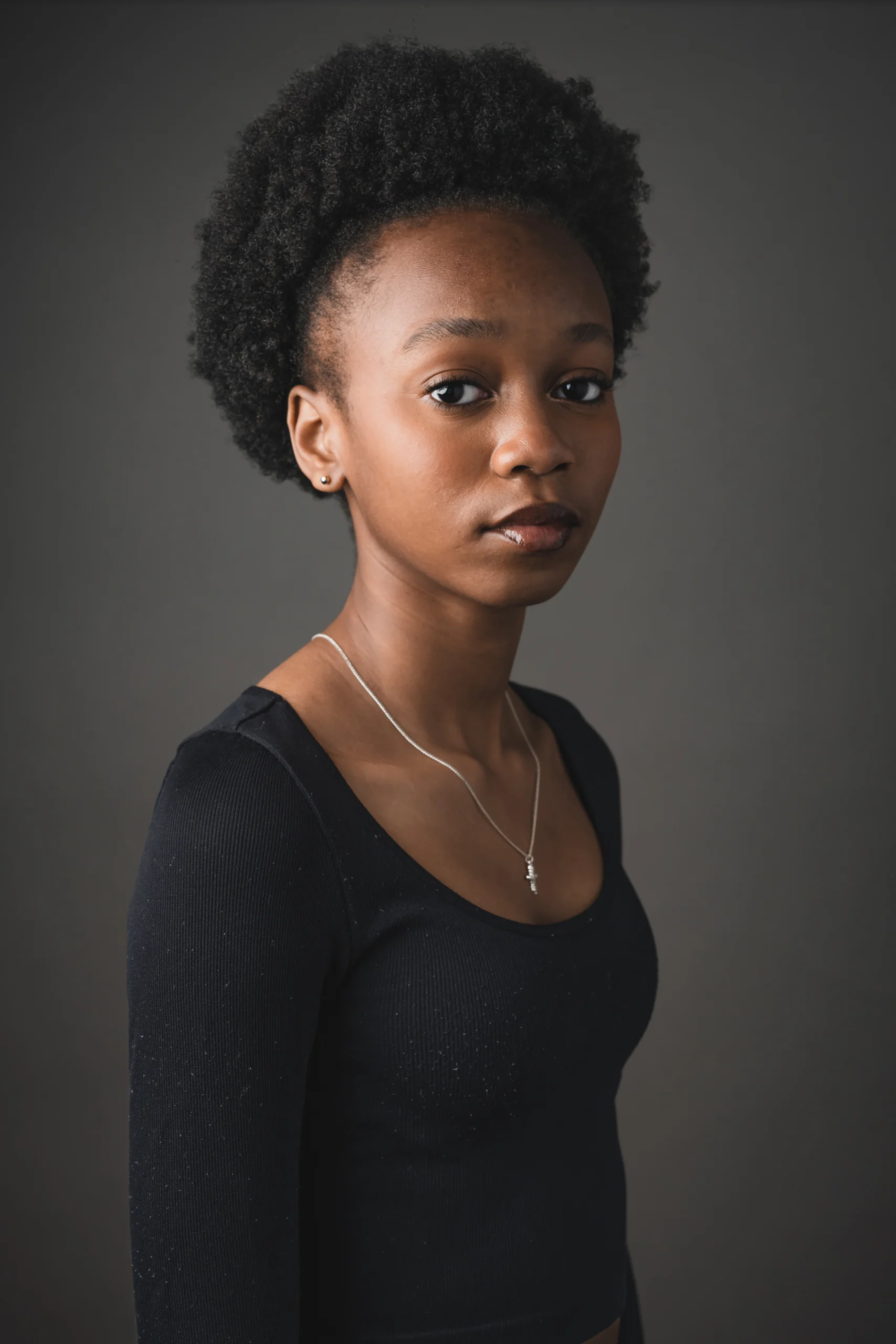 Black girl aged around 13 with short afro style hair in a black t-shirt