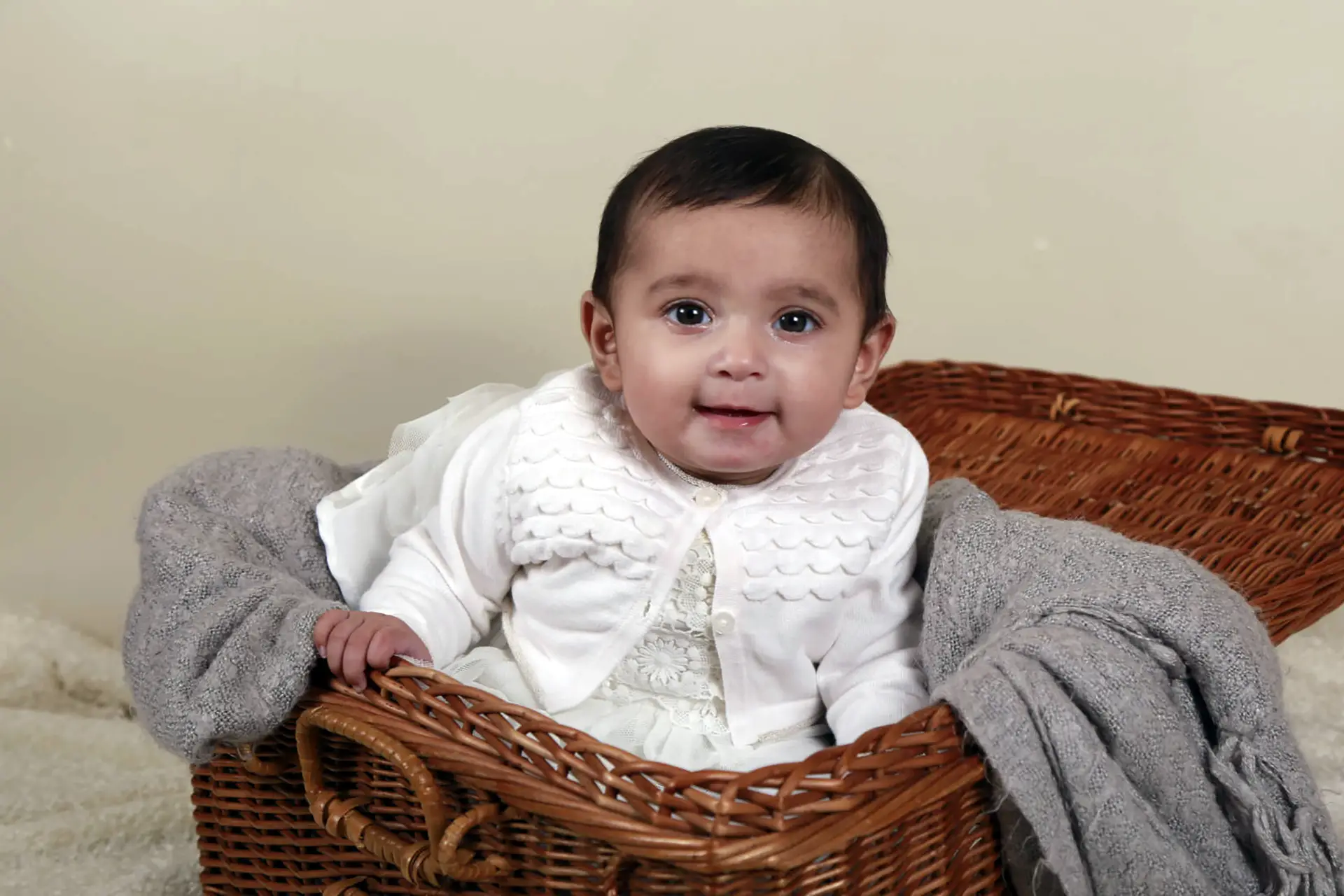 Baby smiling at camera in wicker basket with blanket