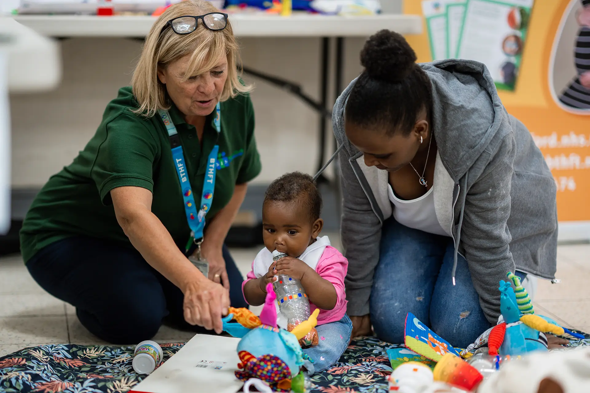 Volunteer pointing at document, with baby and mum