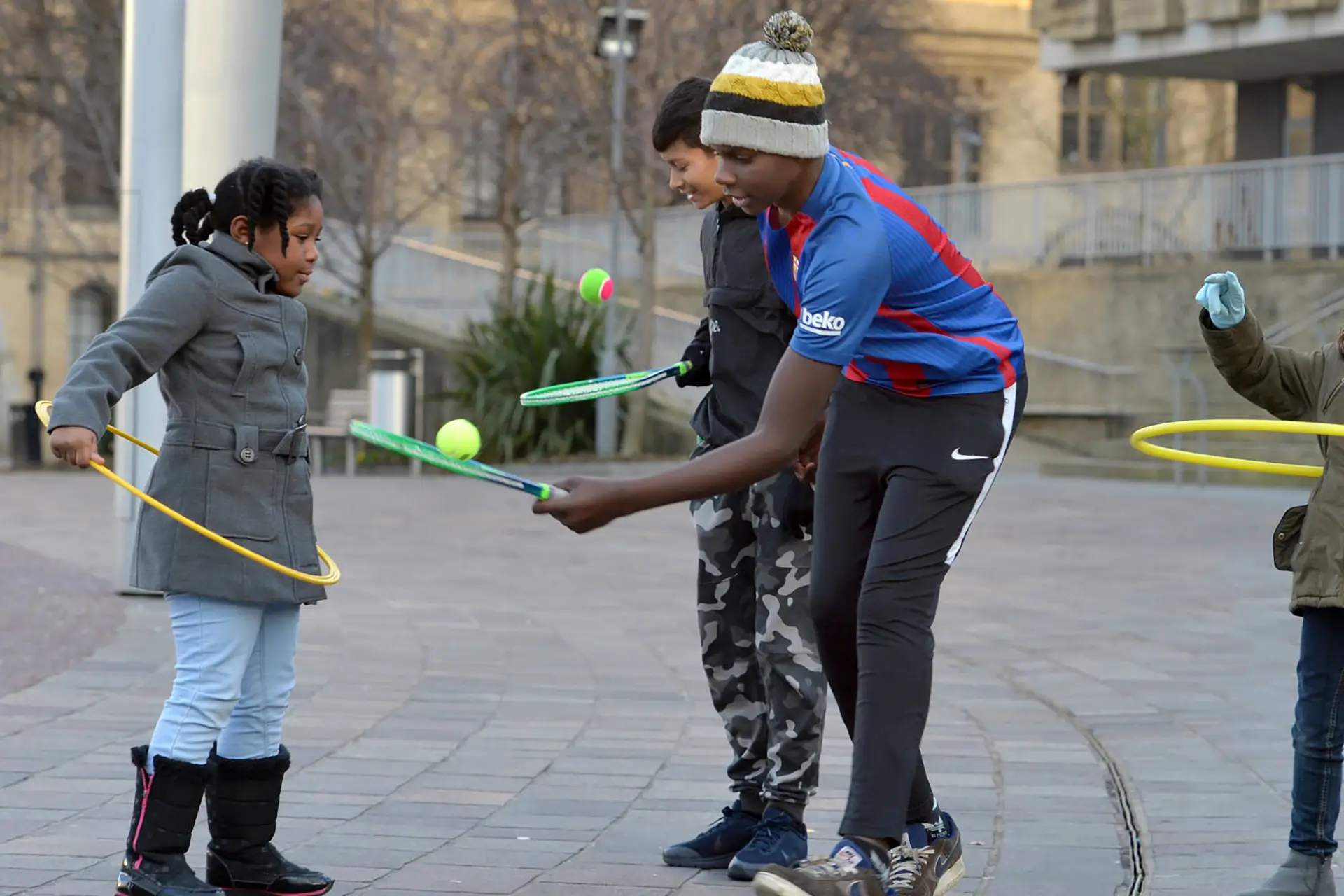 Children playing with rackets, balls and hoolahoops