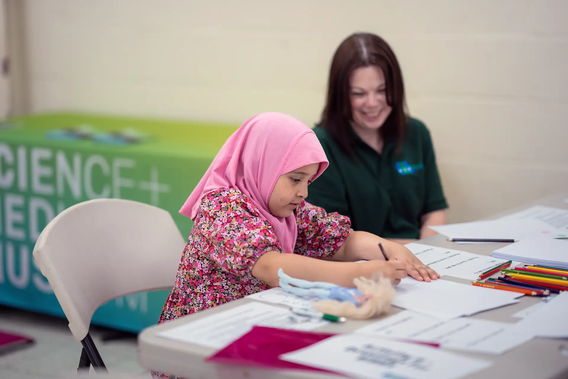 Child working on writing with BiB employee behind watching on