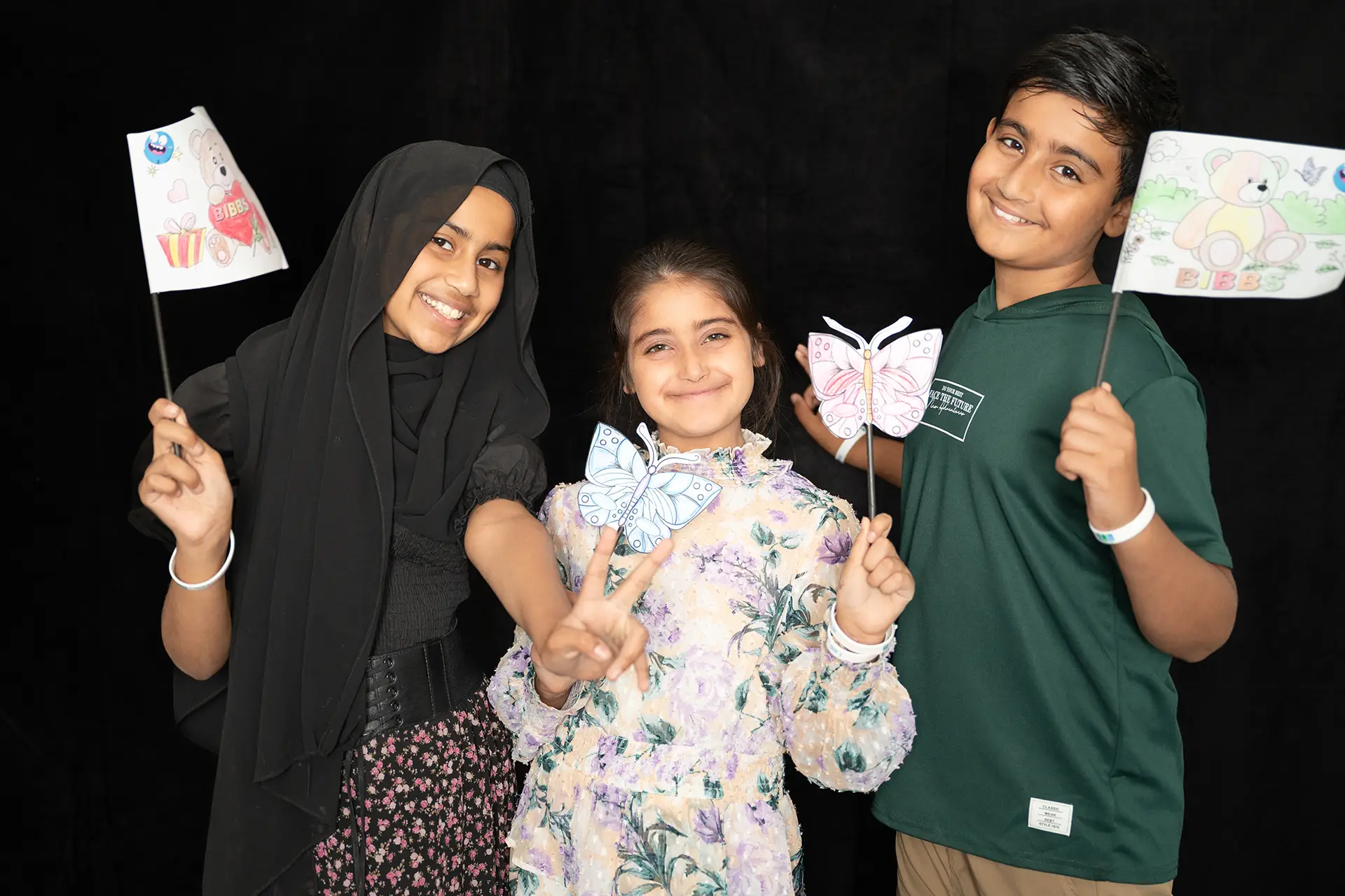 Children posing for photograph with coloured-in flags